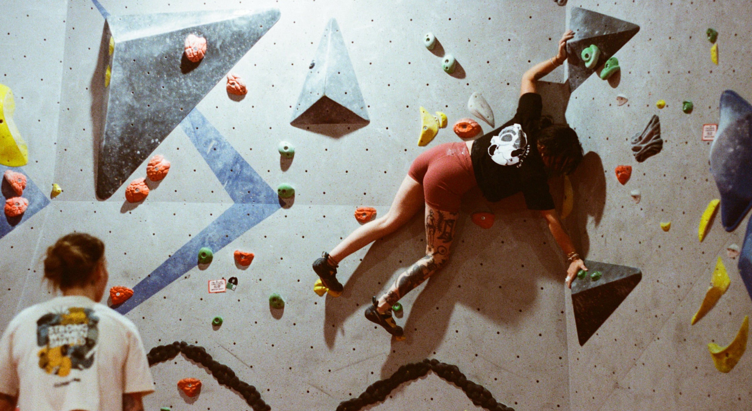 Person climbing a bouldering wall with colorful holds